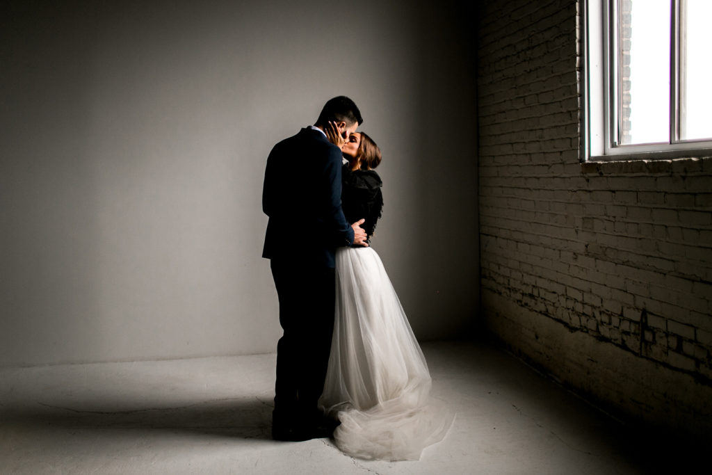 Midwest boho wedding couple kissing in an industrial building.
