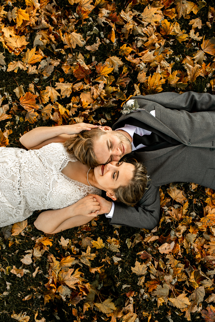 Bride and groom laying in leaves