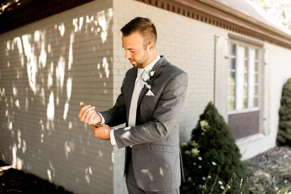 Groom pulls at cuffs as he puts the finishing touches on his wedding day look. 