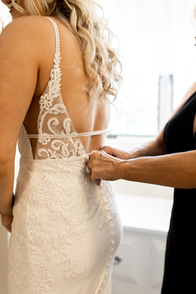 Close up photo of the back of bride's wedding dress, showing off more details of the stunning open back dress. 