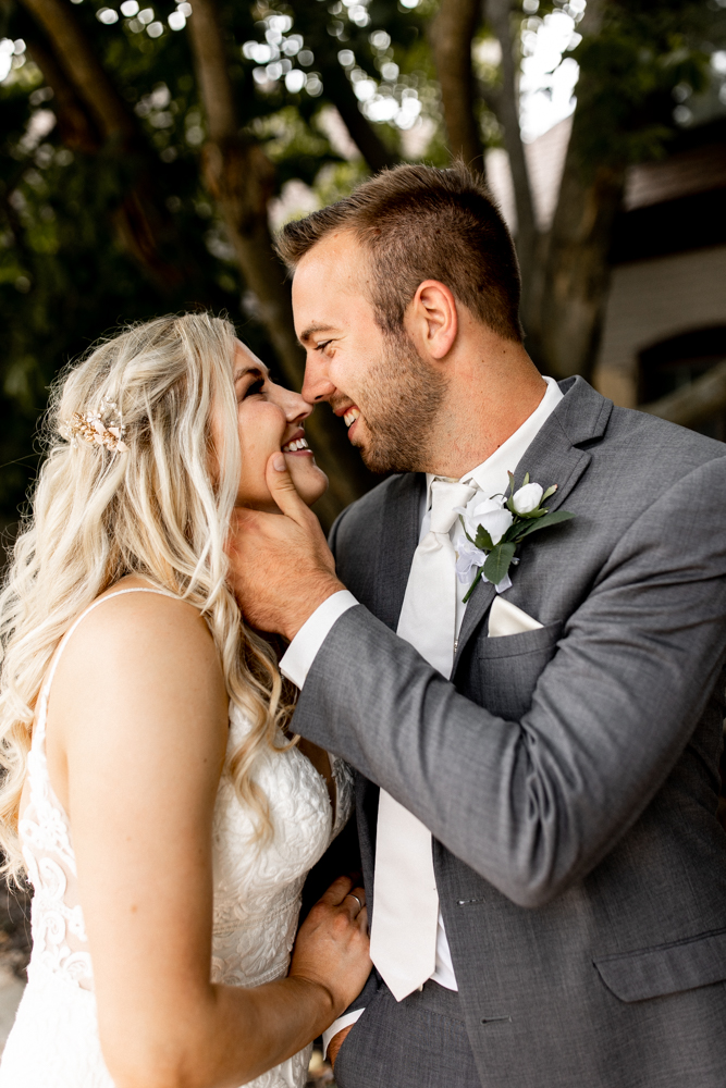 Bride and groom nuzzle noses together and smile adoringly as they look into each others eyes.