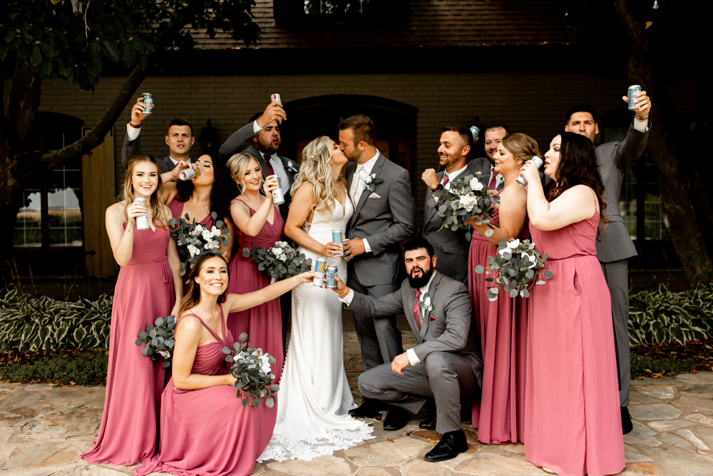 Bride and groom kiss while bridal party cheers around them!