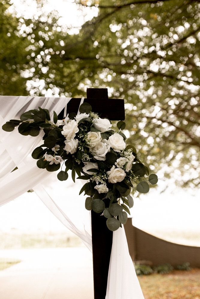 Stunning white roses and green floral arrangement hang to create beautiful wedding ceremony decorations. 
