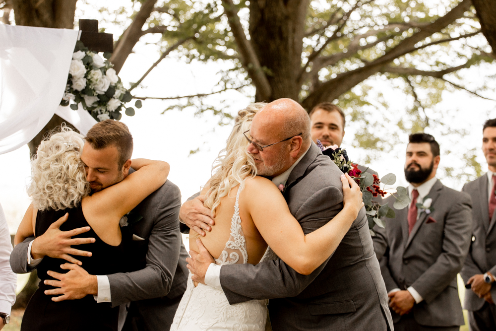 Parents hug bride and groom as they give her away