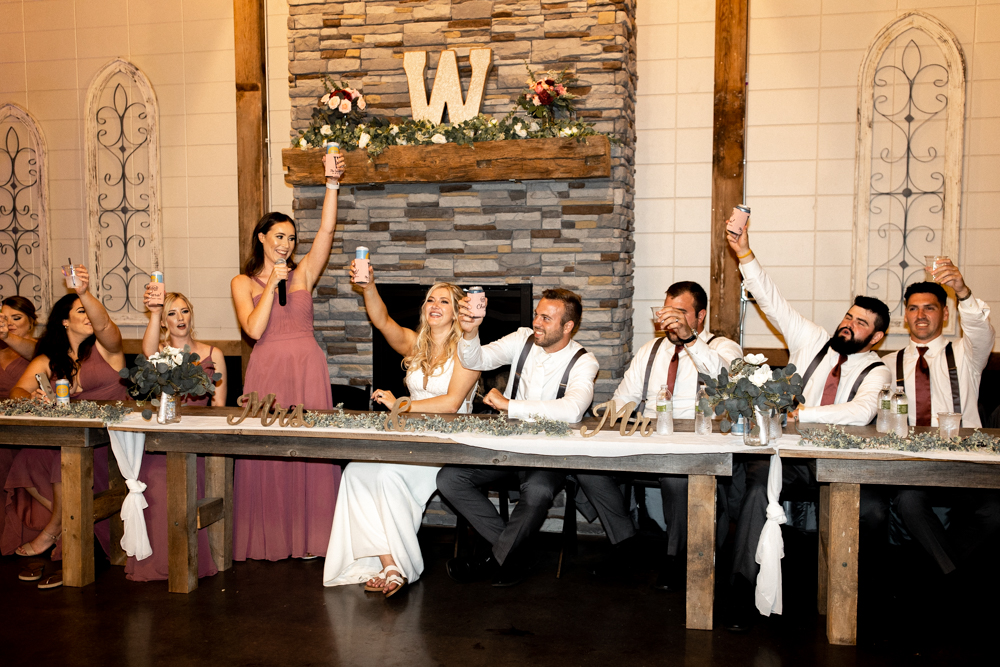 Photo captures bridal party as they all cheers their drinks following wedding speeches.