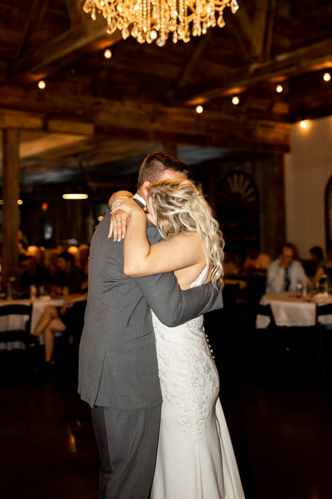 Bride and groom hug during intimate moment as they share their first dance as husband and wife. 