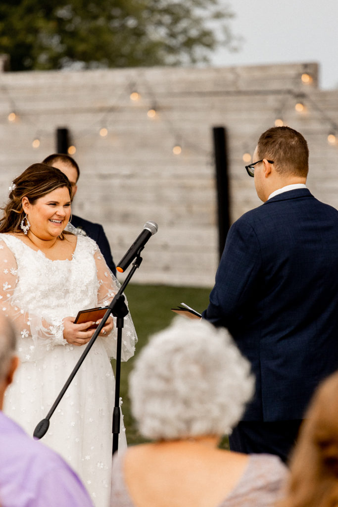 Bride flashes a smile at her groom as she begins to read her wedding vows she has written. 