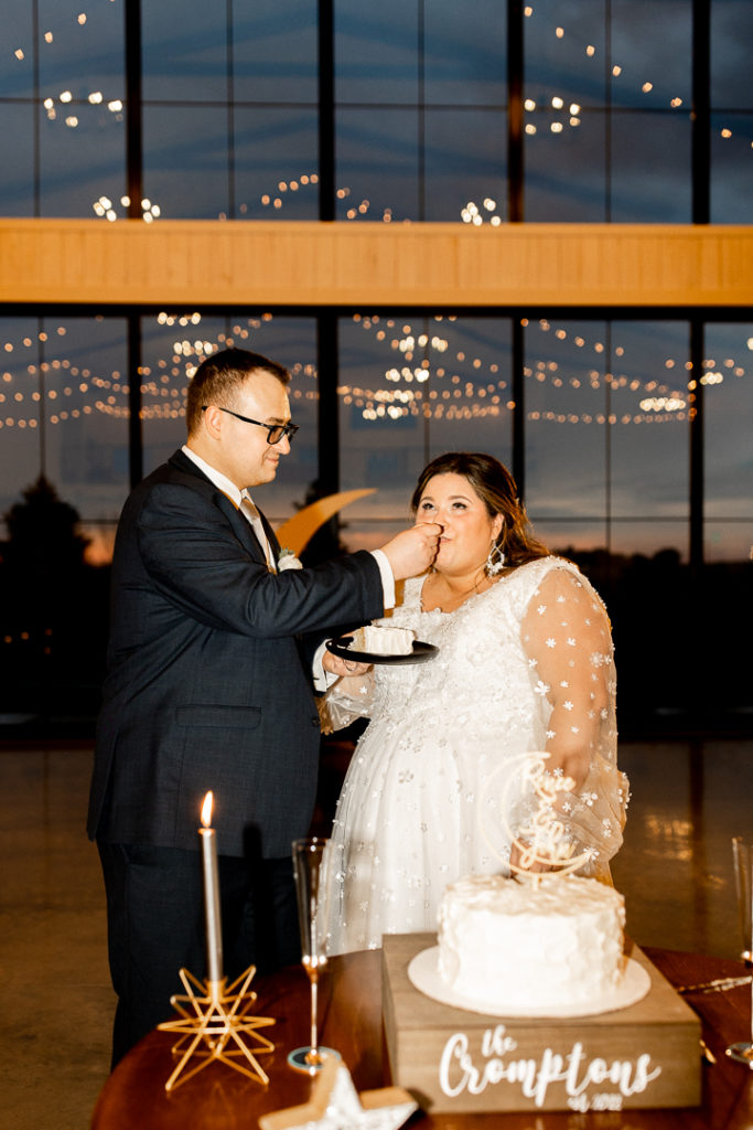 Bride and groom feed each other bites of their wedding cake. 
