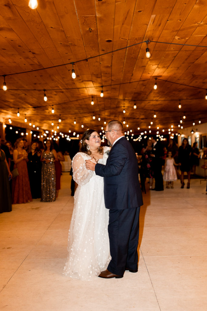 Bride and her dad share a dance as they talk about the beauty of the wedding day. 