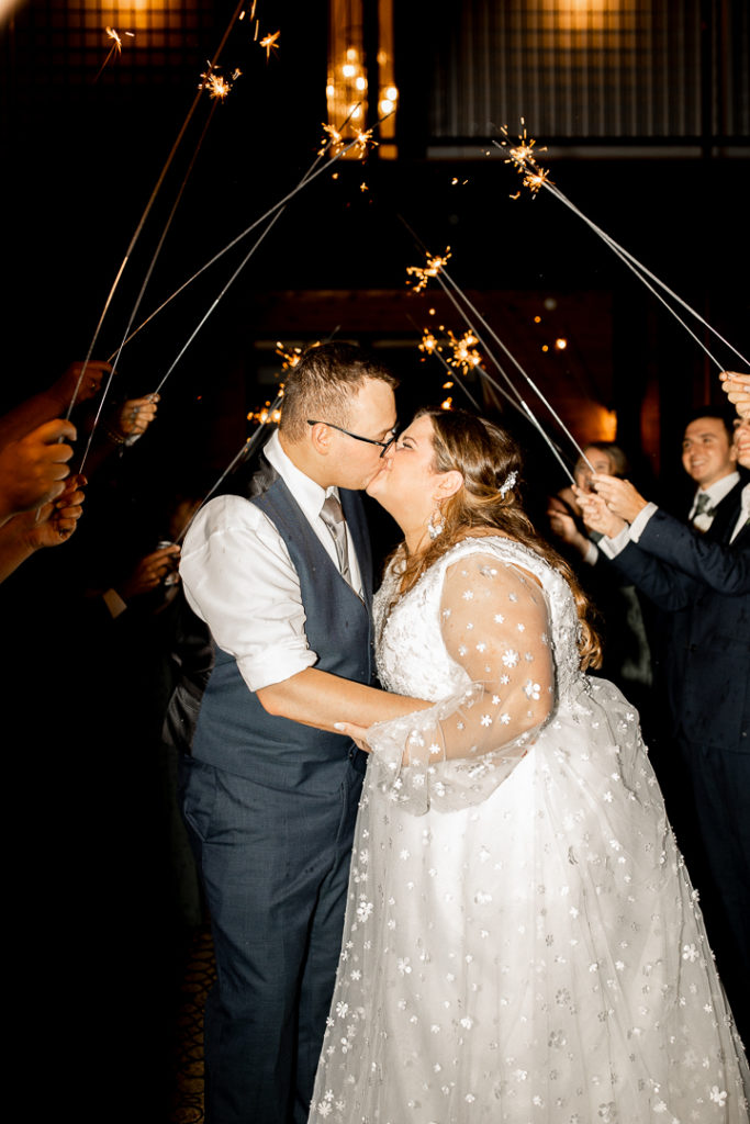 Bride and groom stop for a kiss at the end of their sparkler exit. The perfect ending to their perfect wedding day. Photos by talented Iowa Wedding Photograher. 