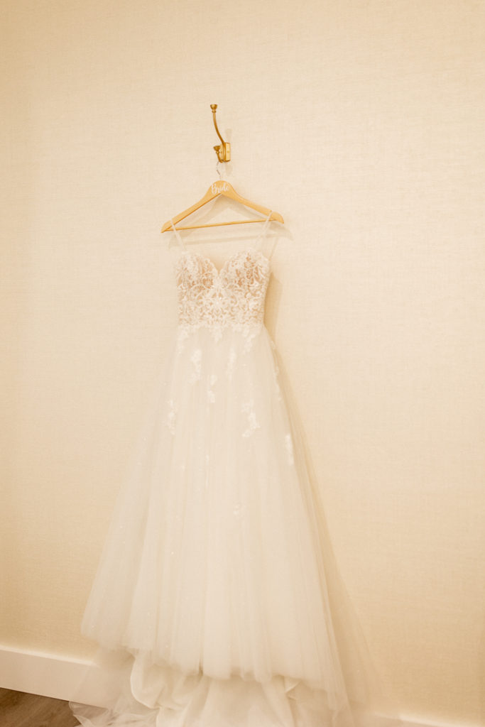 Stunning white wedding dress hanging on wooden "bride" hanger. 