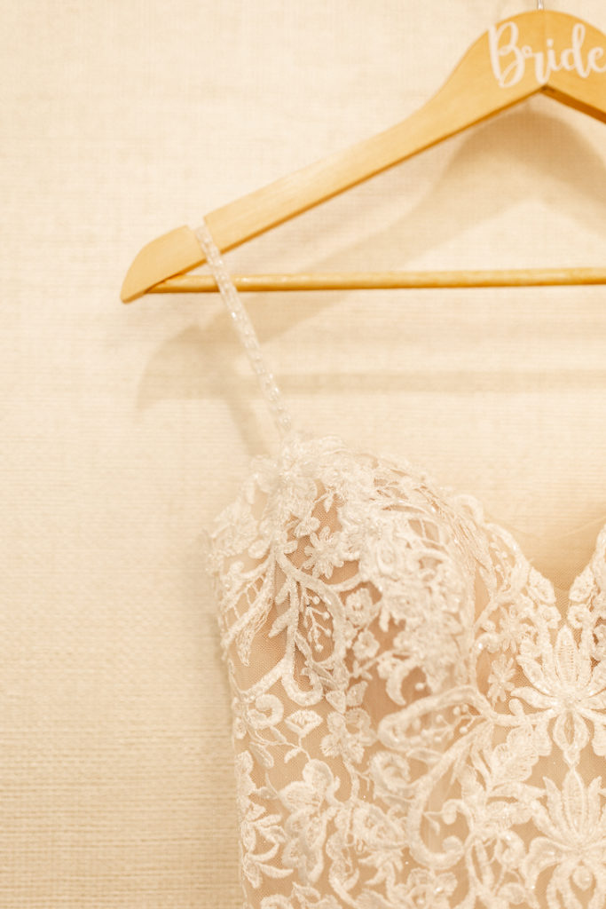 Close up photo of the details of the wedding dress and "Bride" hanger. Gorgeous lace details and skinny straps on absolutely beautiful wedding dress. 