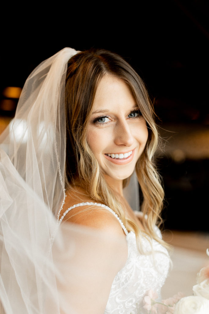 Close up photo of beautiful bride with her hair framing her face and her beautiful veil flowing down.