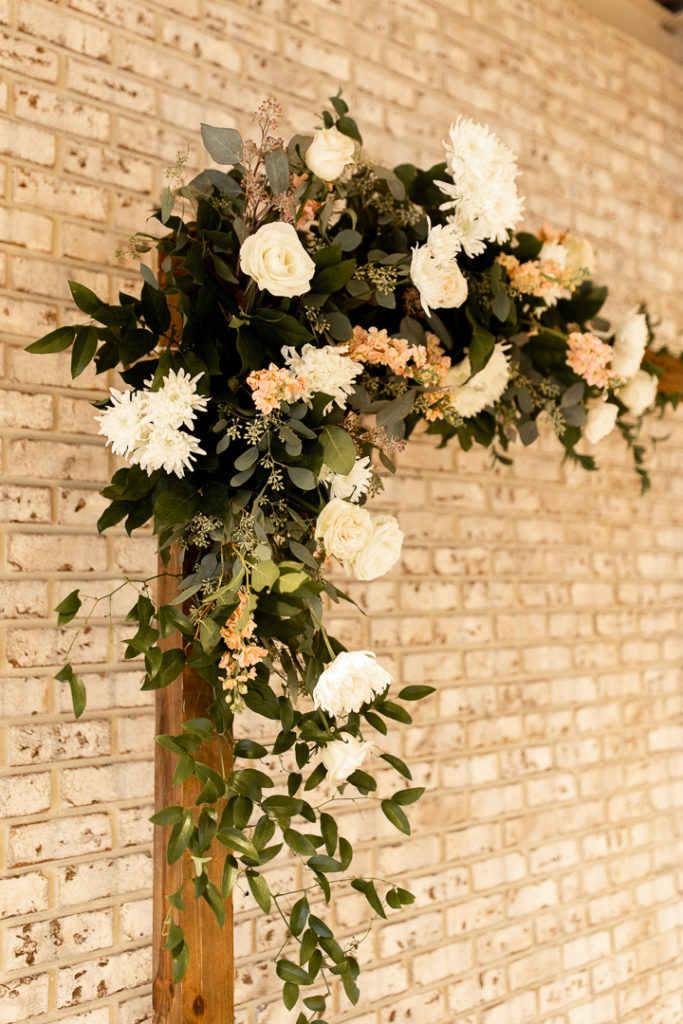 Stunning white and pink flowers with lush greenery drape from the wedding arch as gorgeous wedding day decorations! 