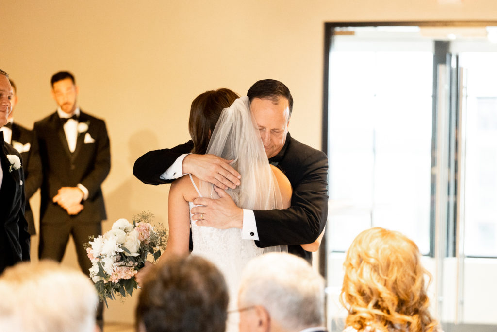 Dad hugs his daughter before he hands her over to her groom. Emotional and sweet moments of the wedding ceremony captured by Iowa Wedding Photographer. 