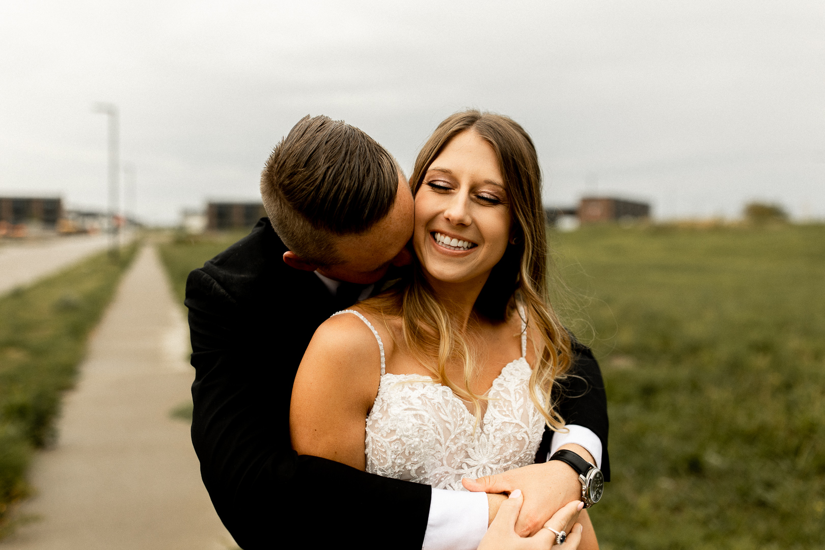 Groom kisses bride's neck on their Iowa Wedding Day,