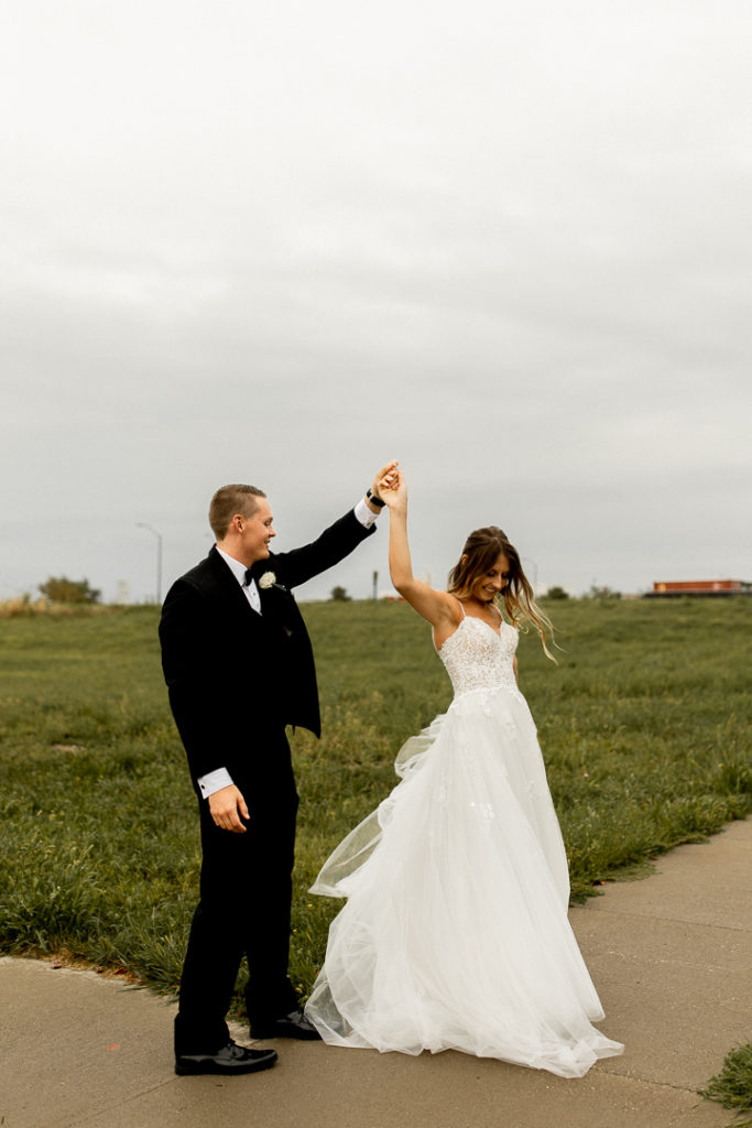The groom twirls his bride as they dance outside their wedding venue Toast in Ankeny Iowa. 