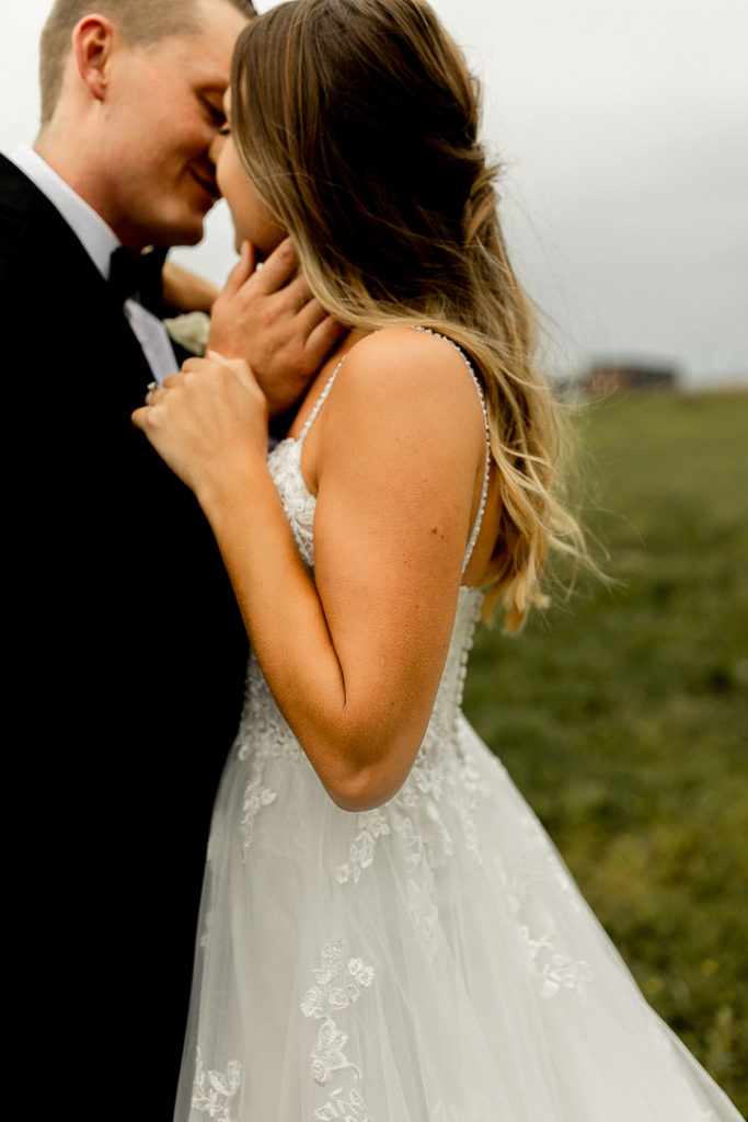 Intimate moments captured by Iowa and Midwest Wedding and Family Photographer. Bride and groom about to go in for a kiss as the groom's hand raises to her neck and her hand raises to his. 