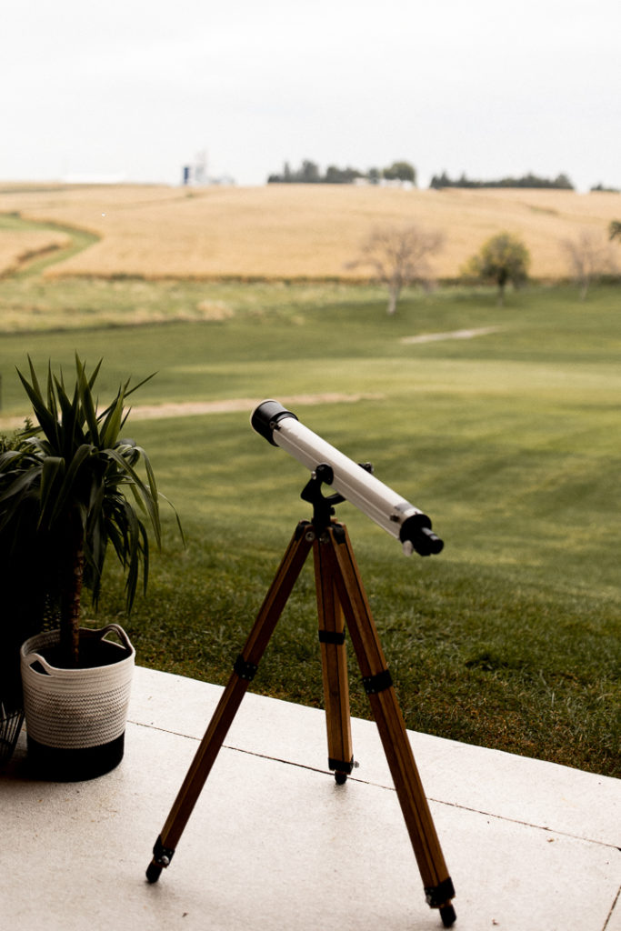 Telescope sits outside waiting for the night sky so guests can look at the stars at this astrology themed wedding ceremony. 