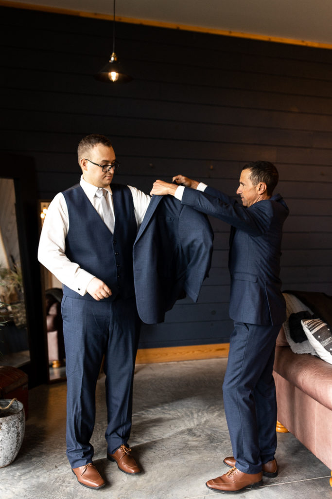 Groom preps for his wedding day as he puts his jacket on. Getting ready photos with the groom captured by Iowa Wedding and Lifestyle Photographer. 