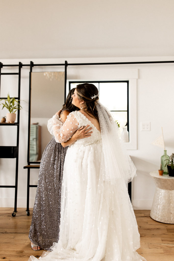 Bride shares a hug with her mom moments before she's about to have first look with bridesmaids. 